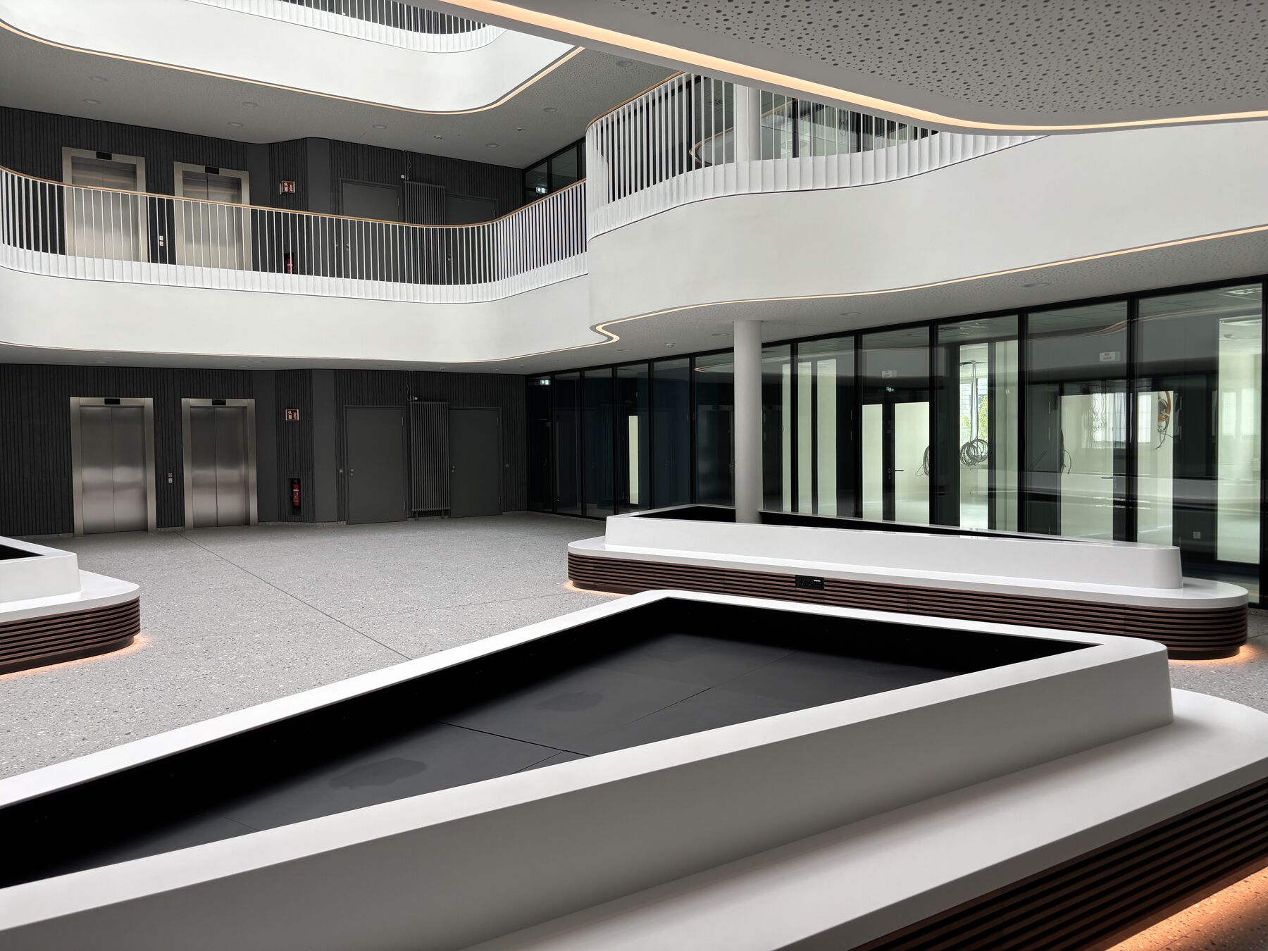 Foyer im Erdgeschoss mit Aufzugsgruppe, Sitzinseln und raumhoher Verglasung